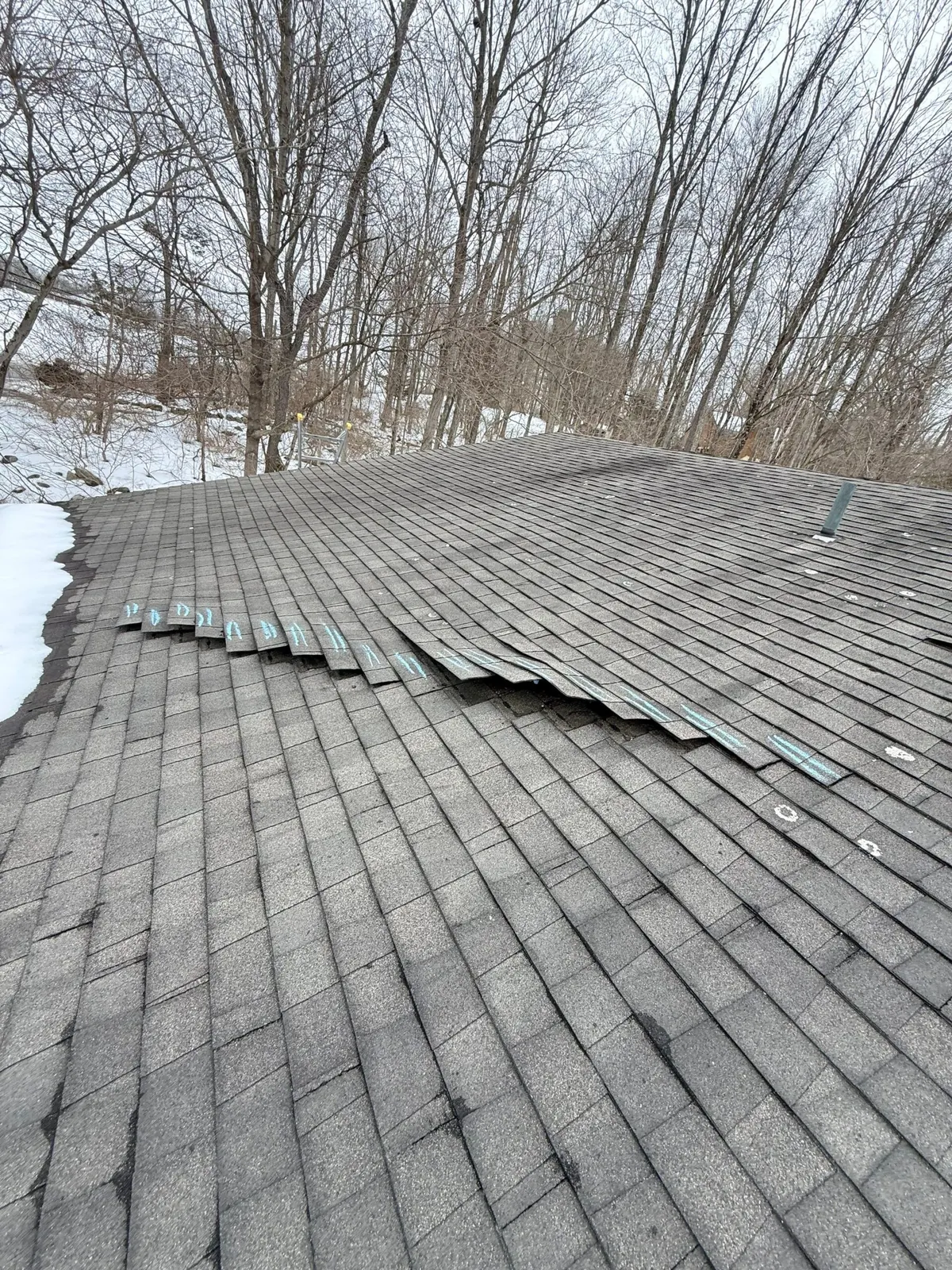 Wind uplift storm damage to asphalt shingles before repair
